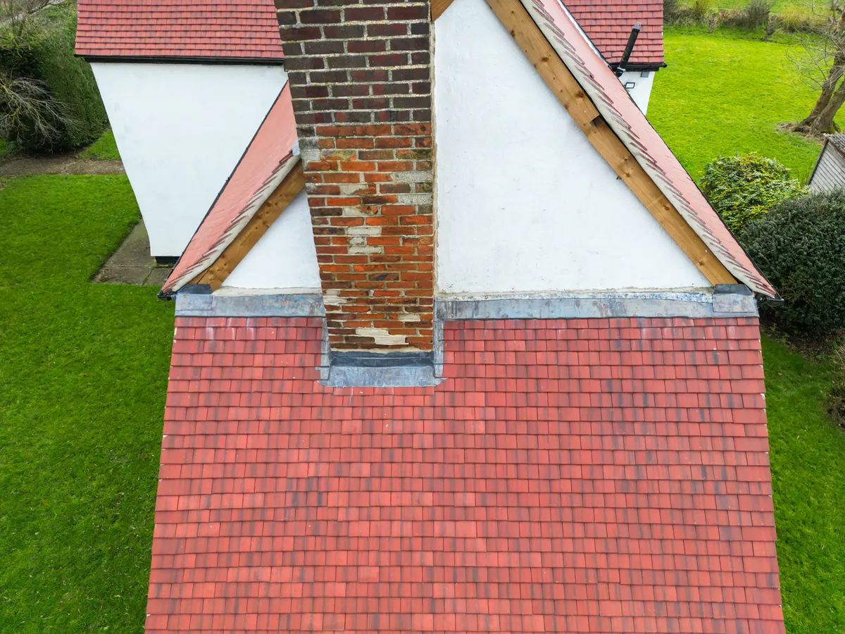 A chimney stack rising from a red tiled roof