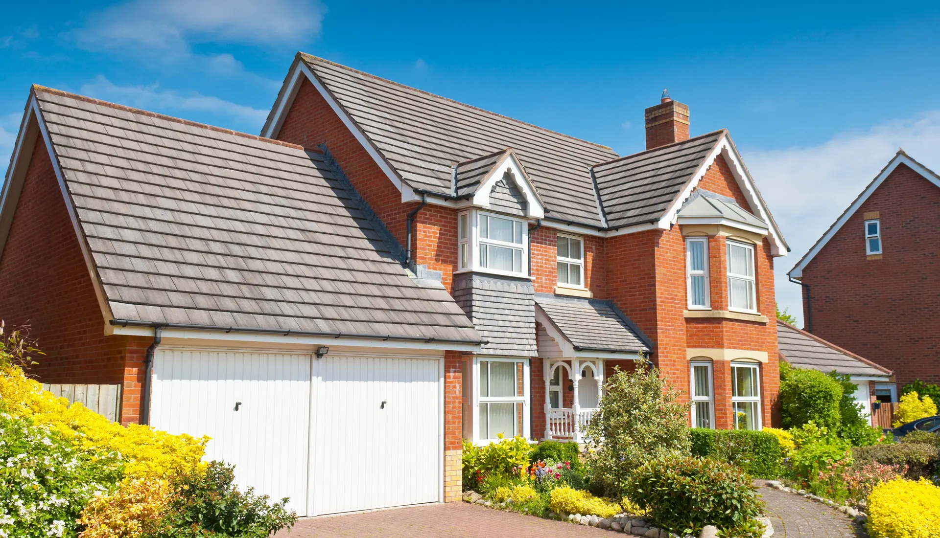 A detached house with a tiled roof and a tidy front garden