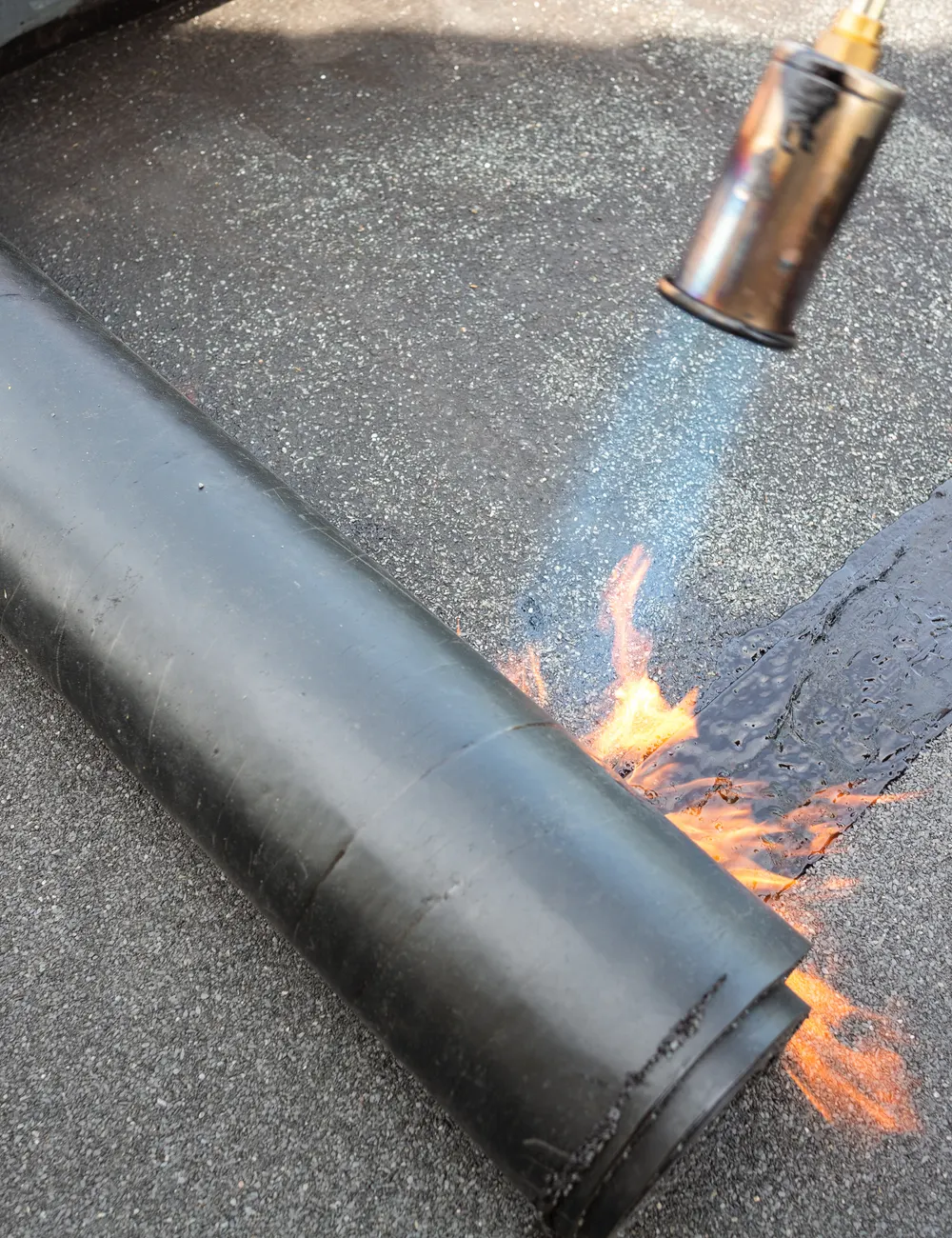 Roofing felt being heated and rolled onto a flat roof