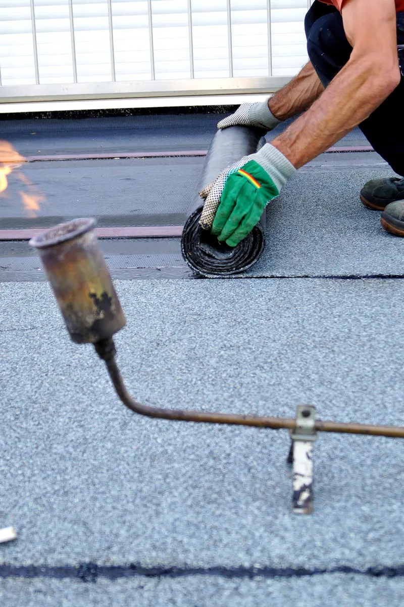 A roofer sealing a felt joint with a gas torch