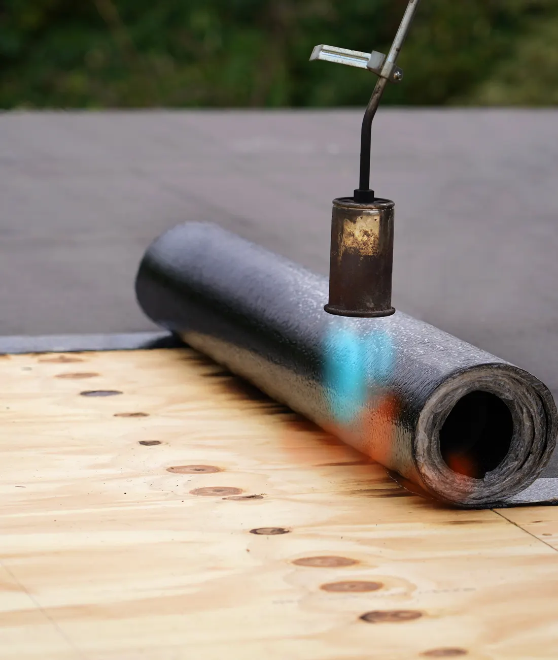 A roll of roofing felt being torched onto a timber deck