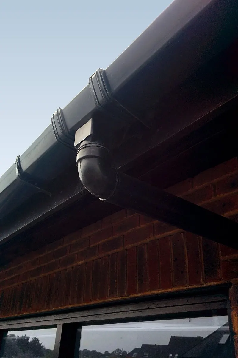 Black guttering and a downpipe outlet under the eaves