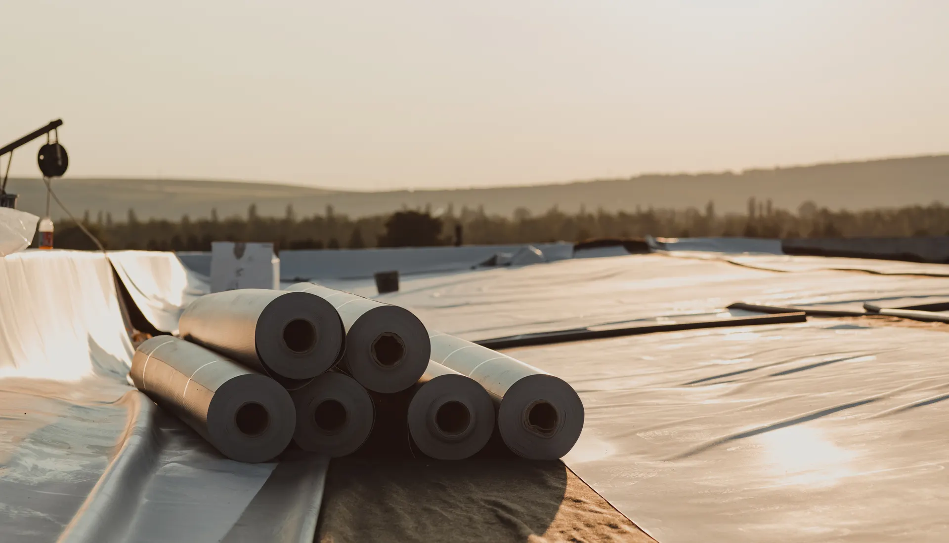 Rolls of rubber roofing membrane laid out on a flat roof