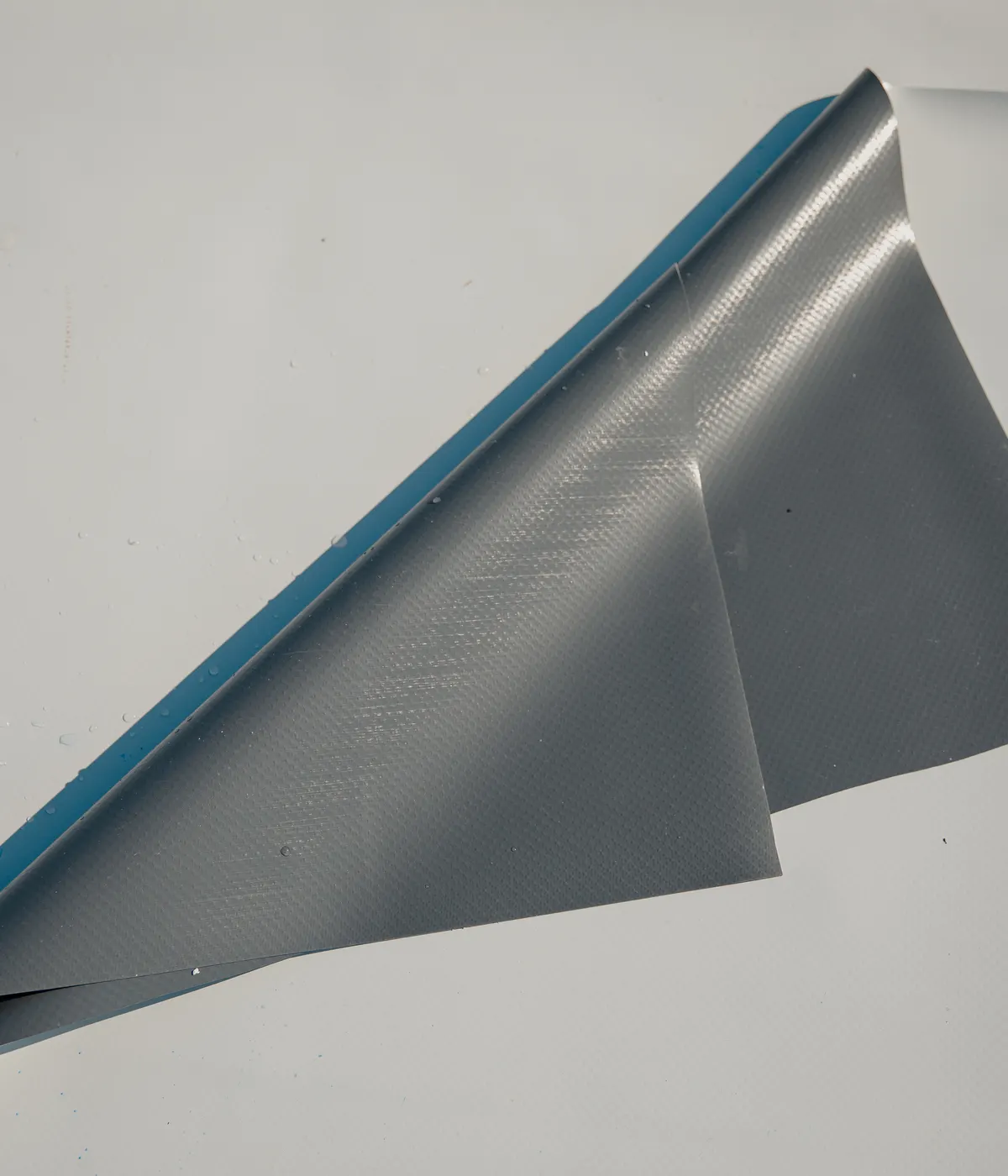 A sheet of rubber roofing membrane being laid at an upstand